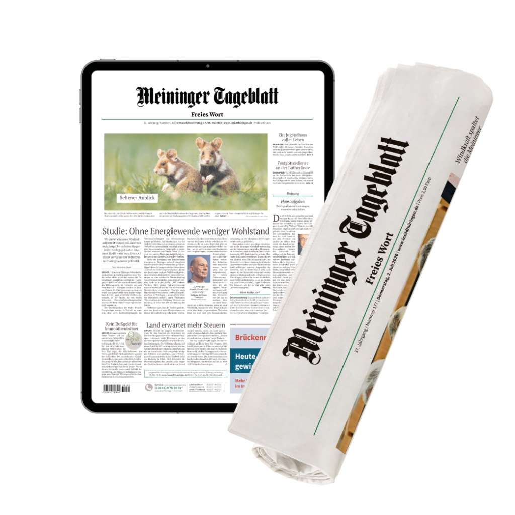 Tablet displaying a German newspaper layout (Meininger Tageblatt) with a rolled print edition beside it.