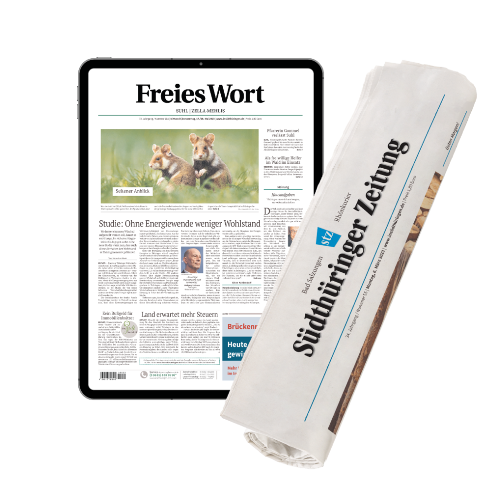 Tablet showing a German newspaper front page 'Freies Wort' beside a rolled print edition of a newspaper titled 'Südthüringer Zeitung'/courier mix of digital+print newsroom.